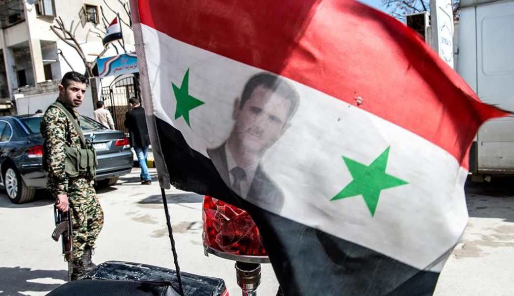 Lars Pehrson/SvD/TT | Flagga med president Bashar al-Assad och regeringssoldat i bakgrunden i östra Aleppo.