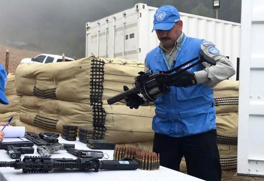 FN/AP/TT | En FN-anställd i Colombia håller i ett vapen som lämnats över av Farc-rebeller.