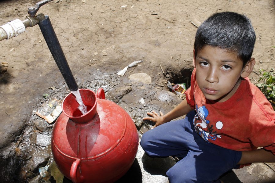 Foto: Edgardo Ayala/IPS | Ett barn fyller en behållare med vatten vid en allmän vattenpump i Los Pinos i staden Ahuachapán i El Salvador.