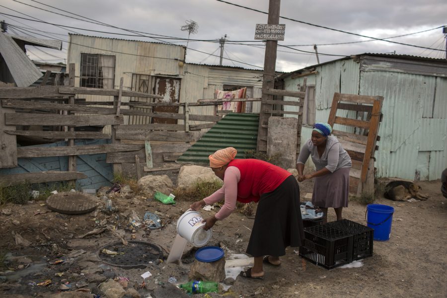 Bram Janssen/AP/TT | En kvinna häller ut avloppsvatten vid ett bostadsområde utanför Kapstaden, som drabbats hårt av torkan.