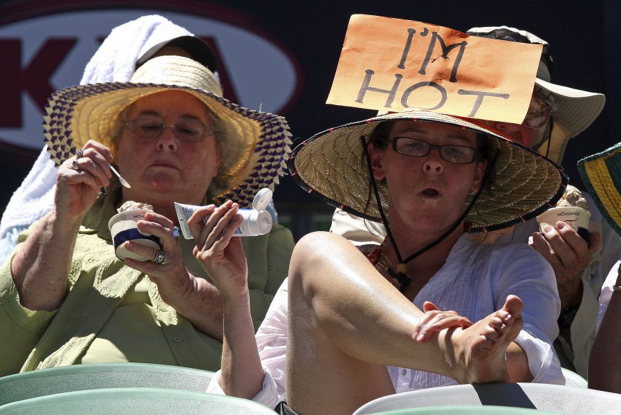 Tennispublik i Australien kör med halmhatt på huvudet och solkräm på benen.