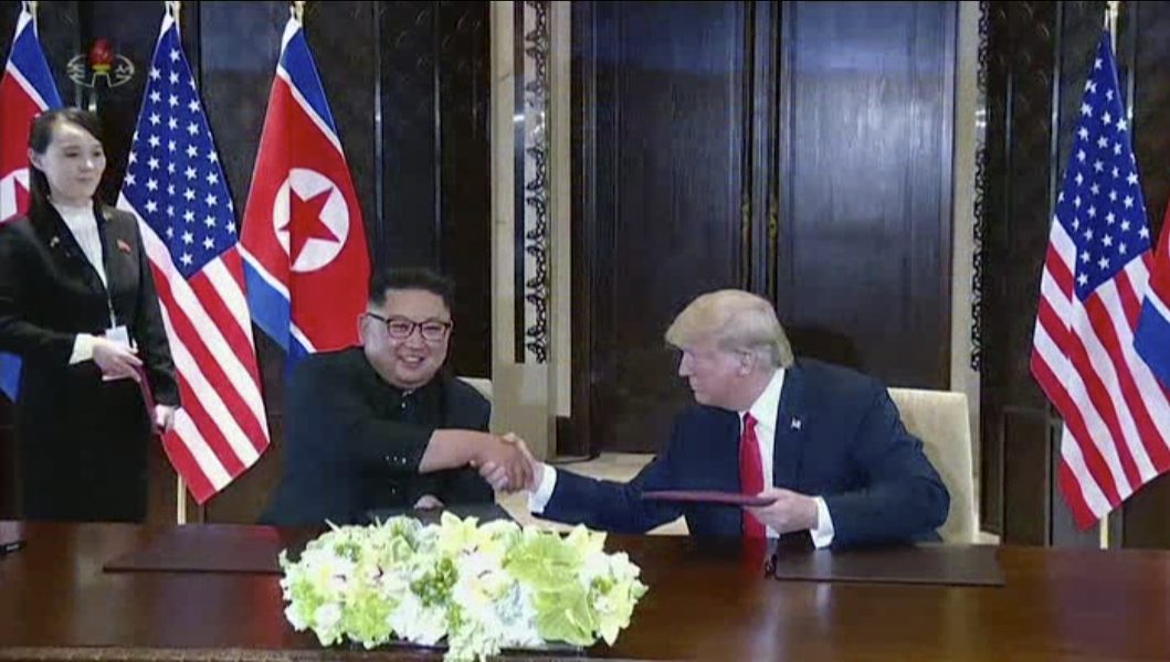 KRT via AP Video | Nordkoreas ledare Kim Jong Un ler och skakar hand med USAs president Donald Trump under mötet I Singapore.