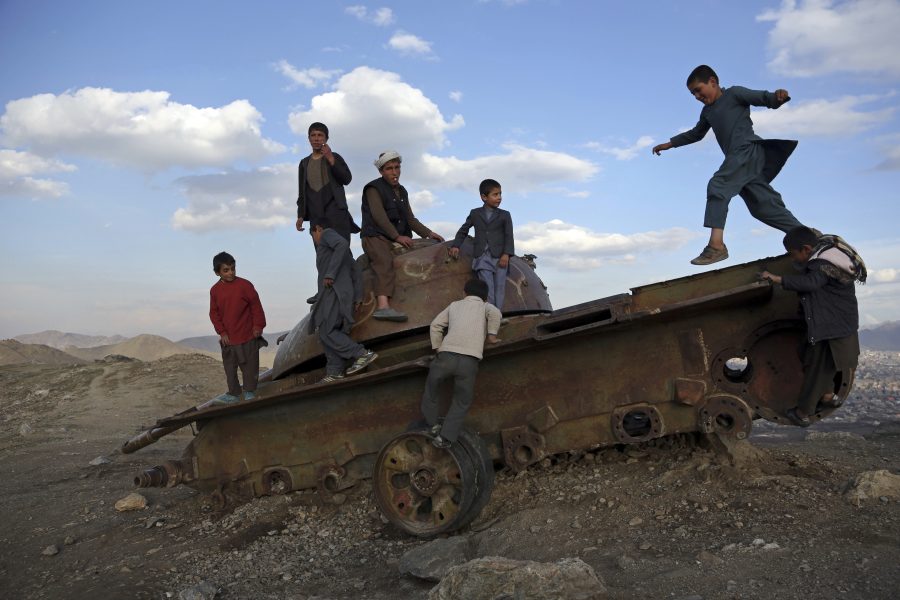 Afghanska barn leker på det som är kvar av en gammal stridsvagn i utkanterna av huvudstaden Kabul.