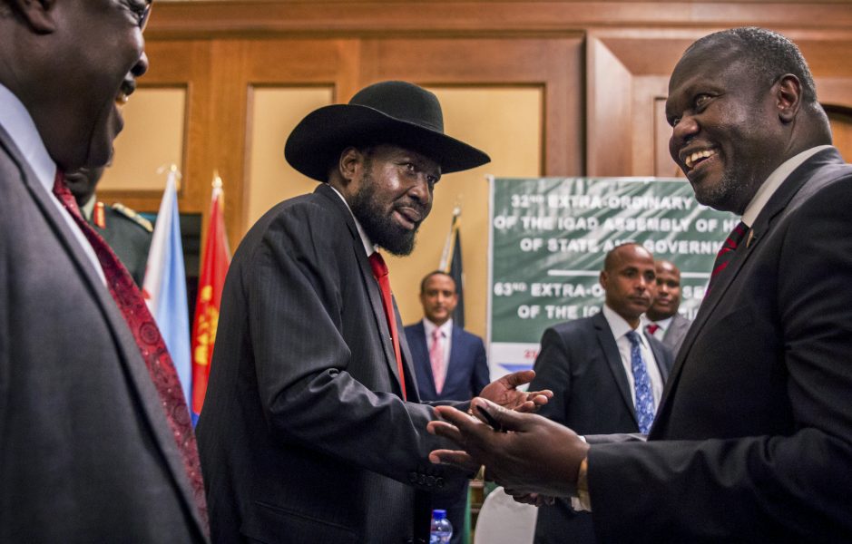 Sydsudans president Salva Kiir, med sin karaktäristiska hatt, till vänster och rebelledaren Riek Machar, till höger, skakar hand.