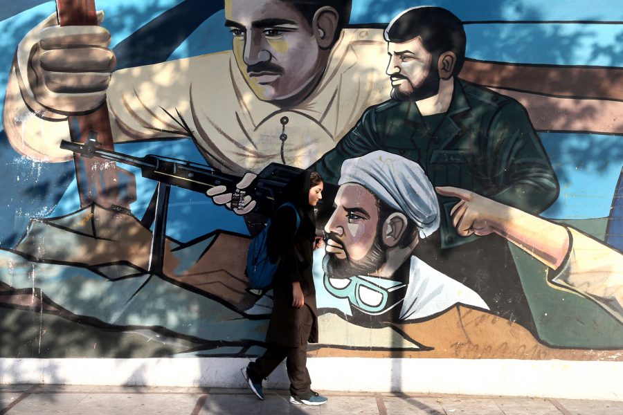 Ebrahim Noroozi/AP/TT | En kvinna går förbi en väggmålning som föreställer medlemmar ur den religiösa frivilligmilisen Basij och som föreställer iransk solidaritet mot landets fiender.