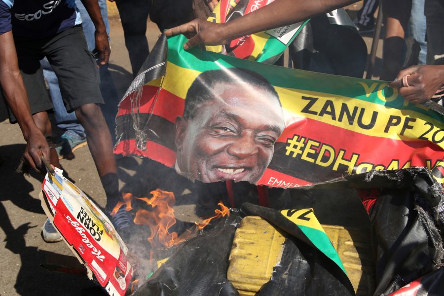 AP Phot/TT | Supportrar till oppositionen MDC bränner affischer av president Emmerson Mnangagwa  vid protester i Harare 1 augusti.