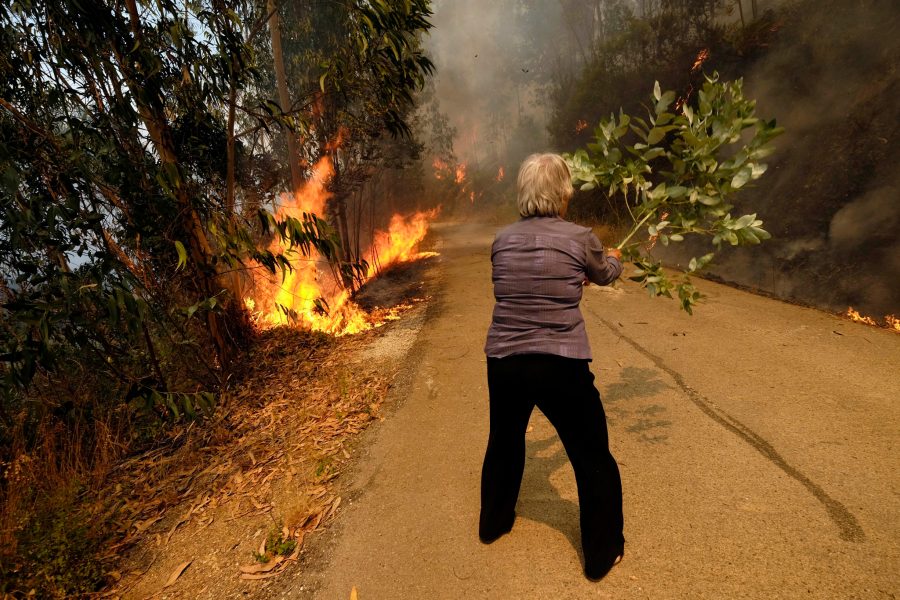 Sergio Azenha/AP Photo/TT | Kvinna försöker släcka brand i Parada, norra Portugal.