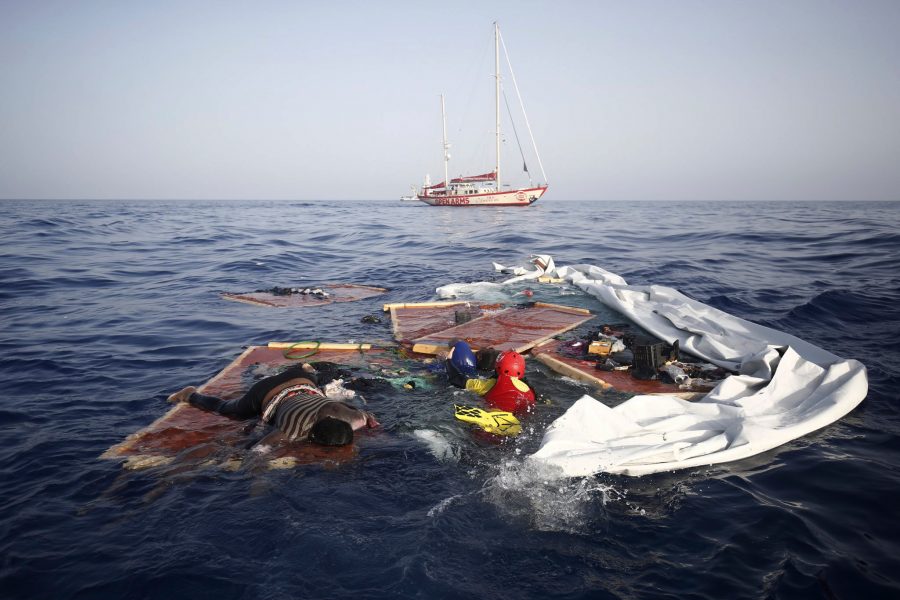 En vuxen och ett barn räddas vid en havererad flyktingbåt nära Libyens kust.