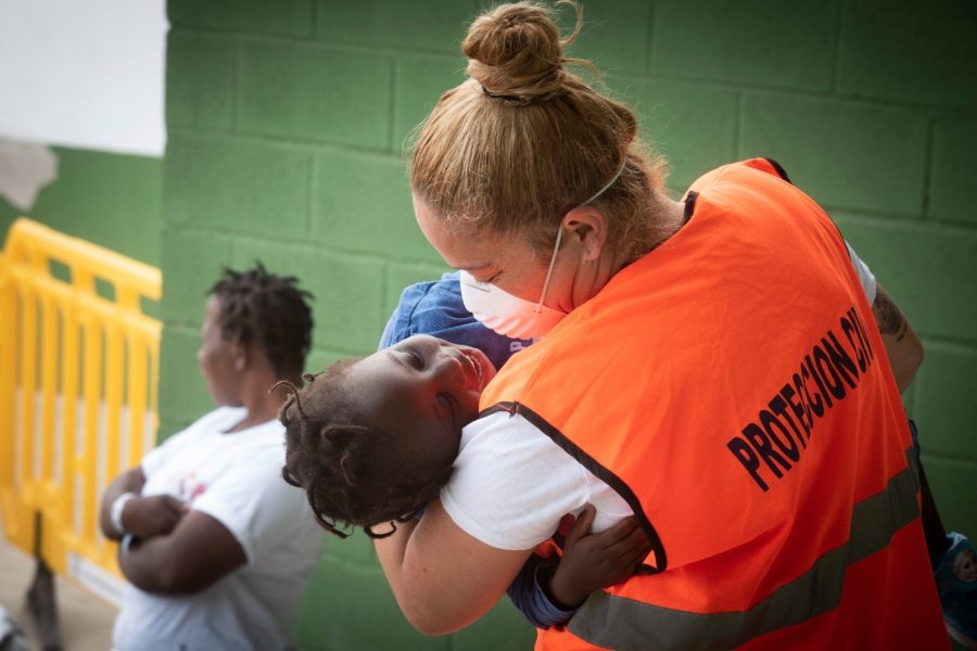 En räddningsarbetare leker med ett barn som räddats i San Roque i södra Spanien.