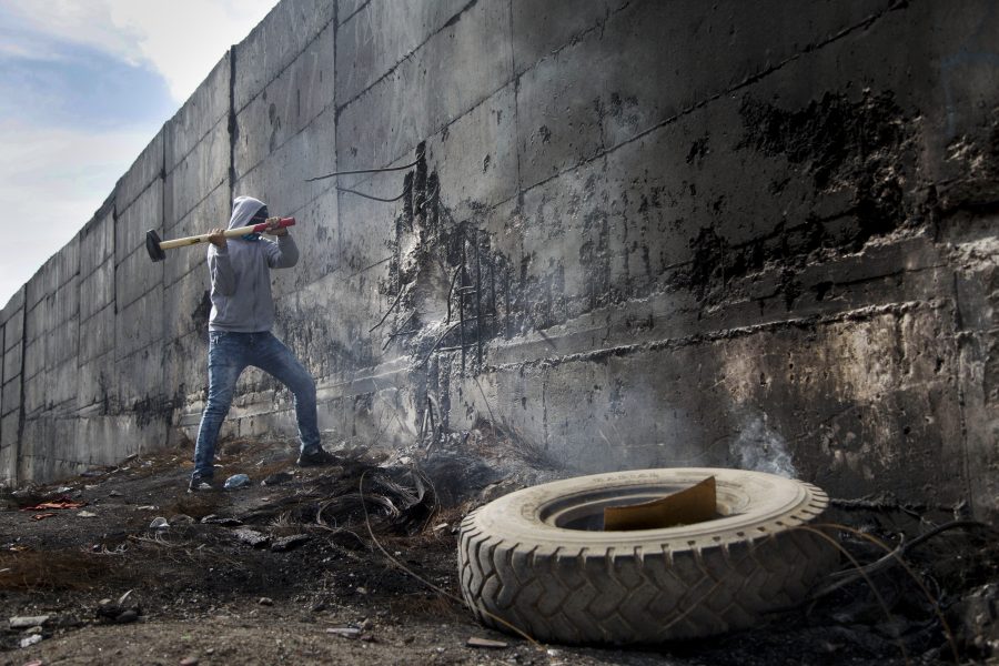 Majdi Mohammed/Ap Photo/TT | Palestinsk student försöker slå hål på muren, som förklarades olaglig av den internationella domstolen i Haag för tio år sedan.