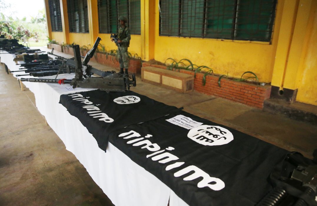 En filippinsk soldat vid vapen, ammunition, uniformer och flaggor som beslagtogs under en offensiv mot IS-kopplade jihadister i staden Marawi i fjol.