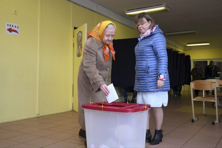 En äldre kvinna lägger sin röst i en vallokal i Riga.