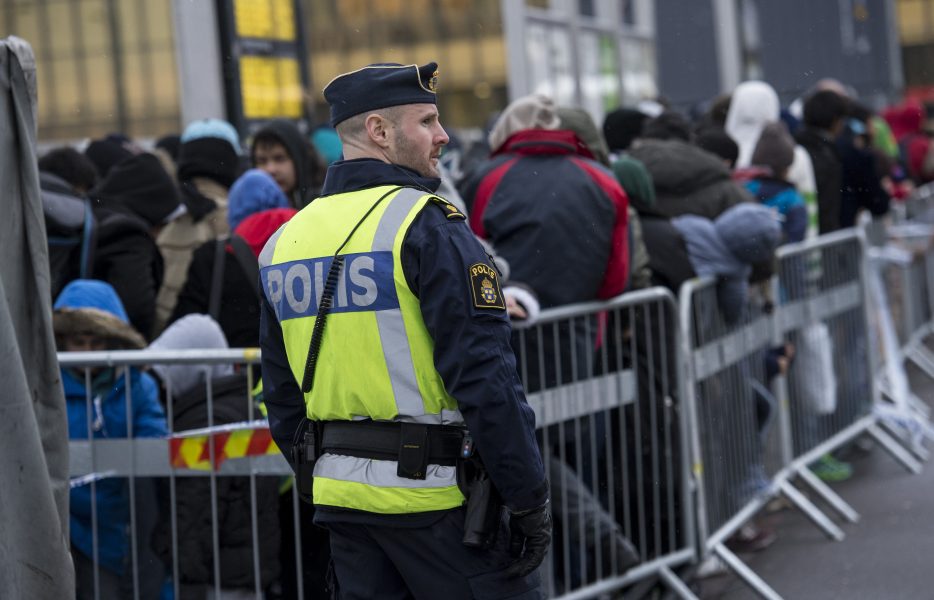 En polis övervakar kön av ankommande flyktingar vid Hyllie station utanför Malmö i november 2015.