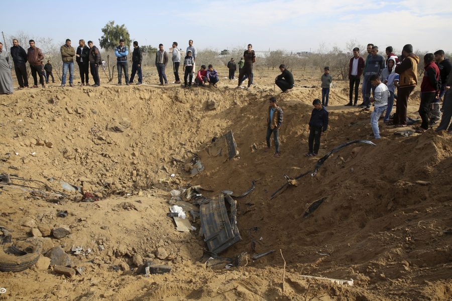 Palestinier beskådar den krater som bildades när ett fordon förstördes i en israelisk militärräd i södra Gazaremsan på söndagskvällen.