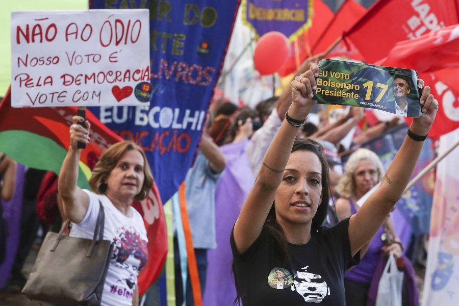 Eraldo Peres/AP/TT | Bakom en supporter till Jair Bolsonaro syns supportrar till Arbetarpartiets kandidat Fernando Haddad med budskap om kärlek.