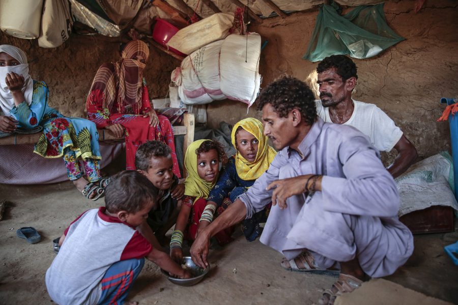 En man ger barn mat i Aslam i Jemen.