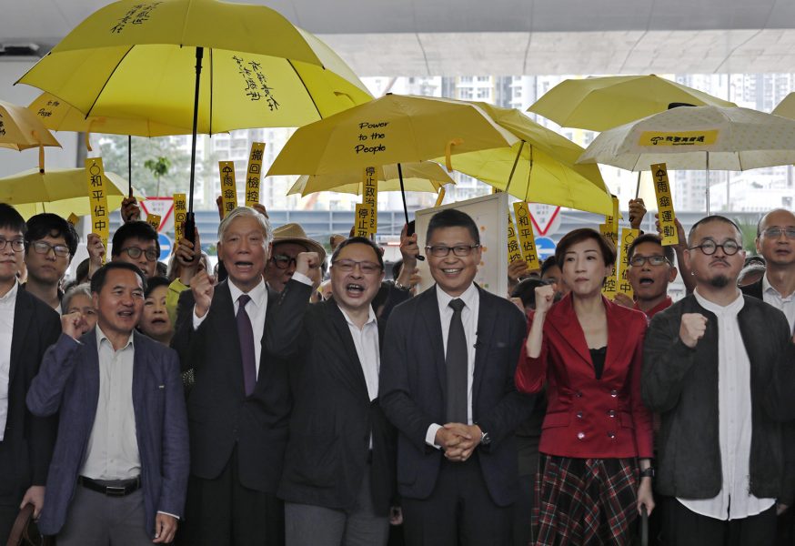 Chu Yiu-Ming, Benny Tai och Chan Kin-Man (de tre i mitten) tillsammans med andra ledargestalter inom "Occupy Central" utanför domstolen i samband med rättegångsstarten på måndagen.
