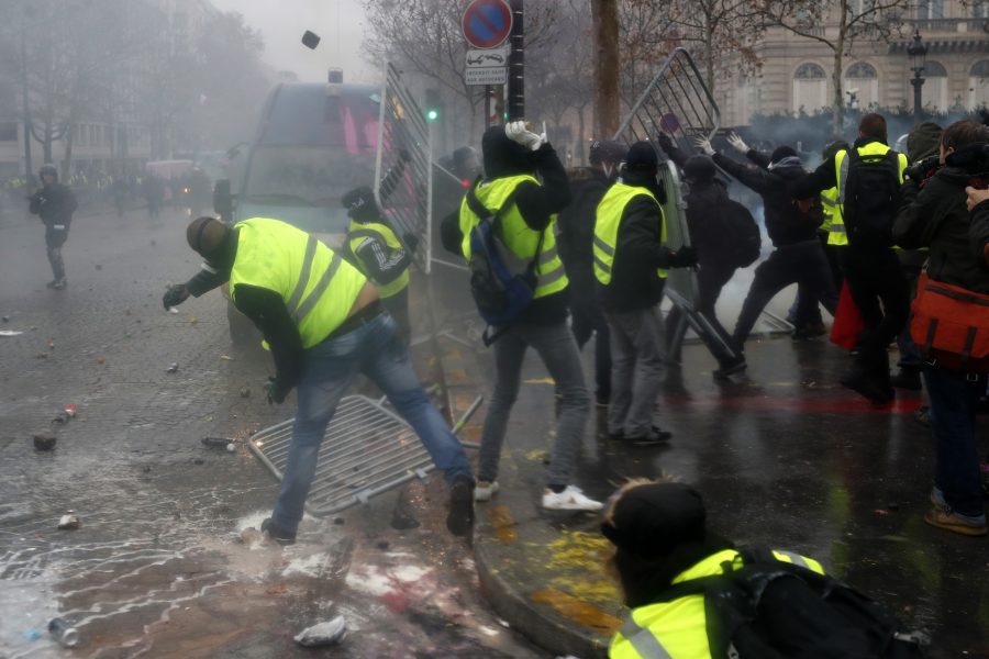 Thibault Camus/AP/TT | Demonstranter kastar avspärrningsstaket mot en polisbil nära Champs-Élysées.