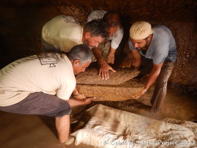 Här lyfter delar av teamet upp en av barnsarkofagerna av sandsten.