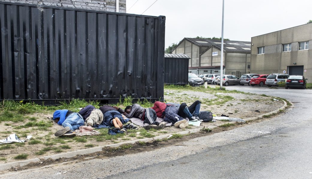 Migranter sover under bar himmel i ett flyktingläger i Calais.