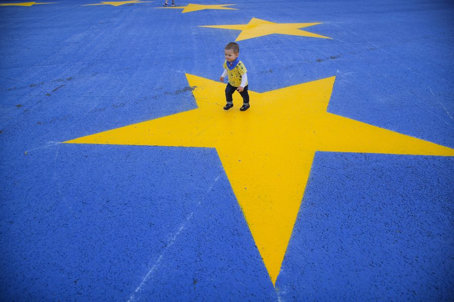 En rumänsk pojke leker på en målad EU-flagga i huvudstaden Bukarest.