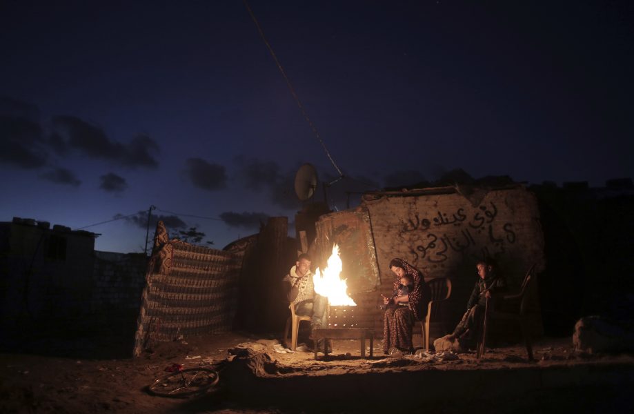 En familj värmer sig vid en öppen eld under ett strömavbrott i södra Gaza.