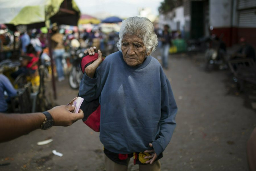 En äldre kvinna blir erbjuden pengar i Caracas, Venezuela.