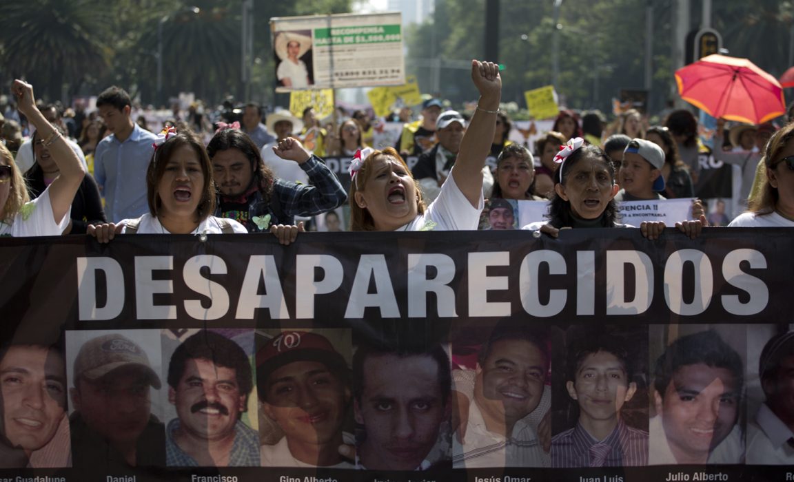 Kvinnor bär en banderoll med bilder på försvunna personer i samband med en demonstration på mors dag i Mexikos huvudstad Mexico City i våras.