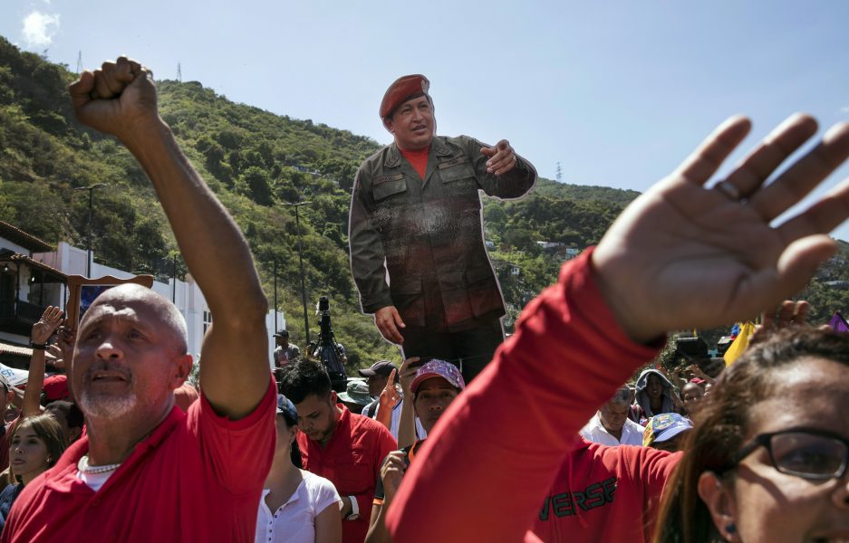 Maduro-supportrar håller upp plakat med bild på förre presidenten Hugo Chavez vid en demonstration i La Guaira, Venezuela, 25 jan.