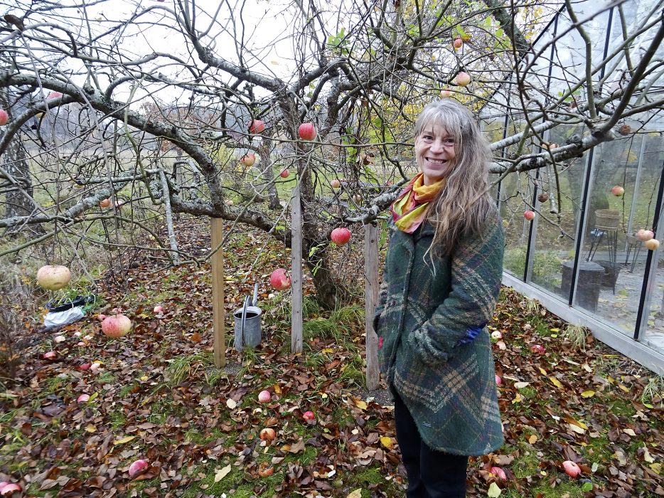 Eva Solhäll vid äppelträdet som växer och frodas i hälsoträdgården.