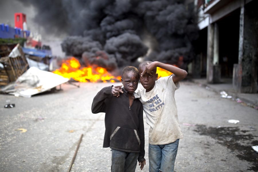 Hemlösa barn poserar framför brinnande barrikader efter protesterna som kräver president Jovenel Moïses avgång.