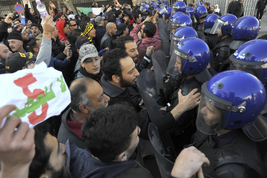 Demonstranter och poliser under fredagens protester i Alger.
