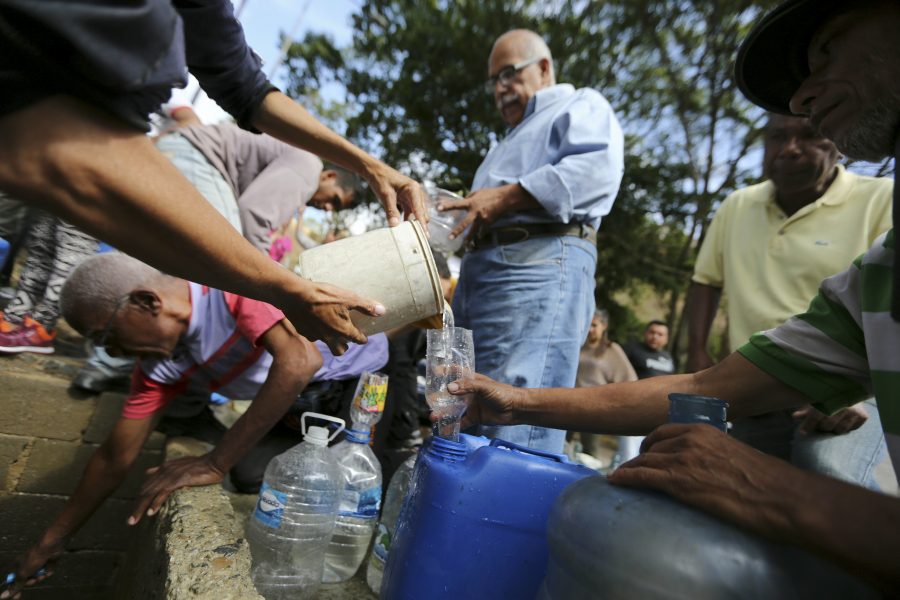 Människor samlar vatten ur en trasig vattenledning i Venezuelas huvudstad Caracas.