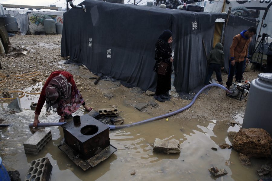 En flyktingfamilj från Syrien försöker pumpa bort vatten efter skyfall över det flyktingläger i staden Bar Elias i Libanon där de bor.
