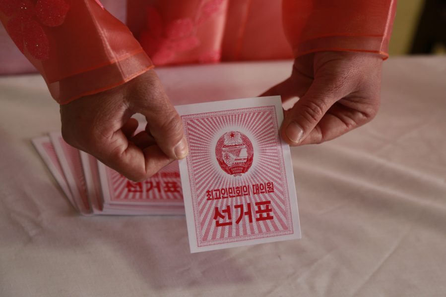 En valarbetare visar en valsedel i en röstlokal i huvudstaden Pyongyang i Nordkorea.