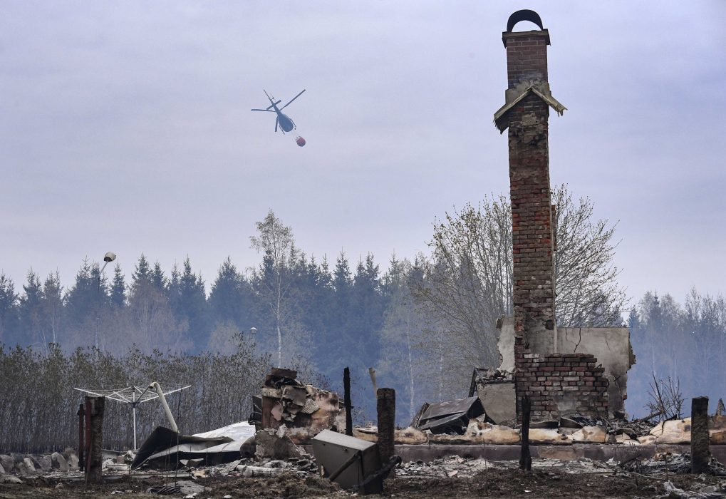 En helikopter vattenbombar skogen bakom den nerbrunna hästgården vid Tulatorp utanför skånska Hästveda på onsdagen.