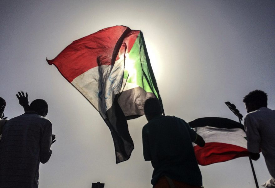 Sudanesiska demonstranter med landets flagga utanför militärens huvudkvarter i Khartum.