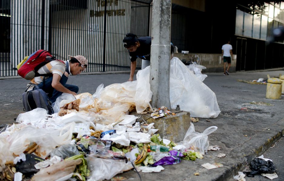 Män som letar efter mat i en sophög i Caracas.