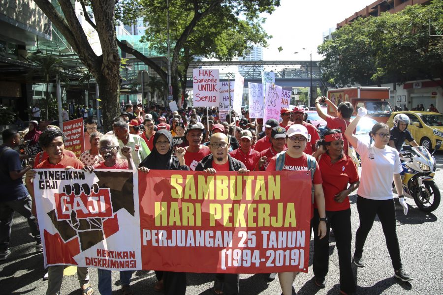 Demonstranter i Kuala Lumpur, Malaysia håller upp en banderoll med orden "höj lönen och stoppa diskrimineringen".