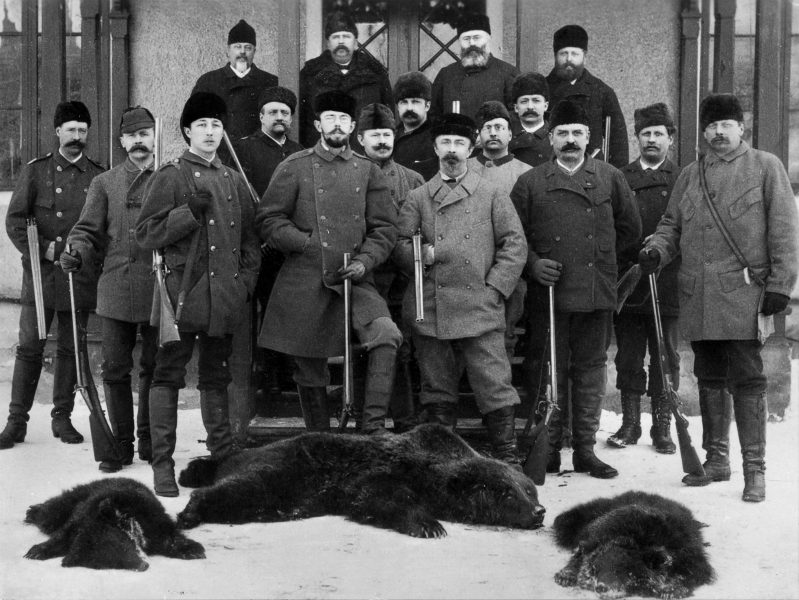 Kung Gustav V och hans jaktlag poserar bakom en nermejad björnfamilj 1886.