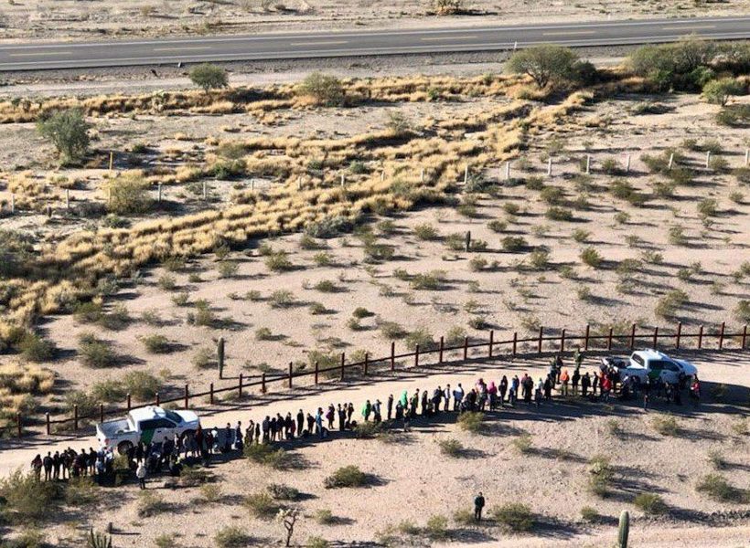 Migranter står på rad i öknen vid den amerikansk-mexikanska gränsen, nära Lukeville, Arizona.