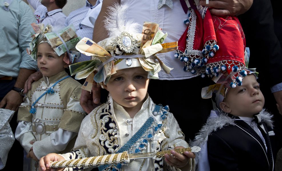 Tre små killar i folkdräkt och mössor fyllda med sedlar på "omskärelsefestival" i Bosnien.