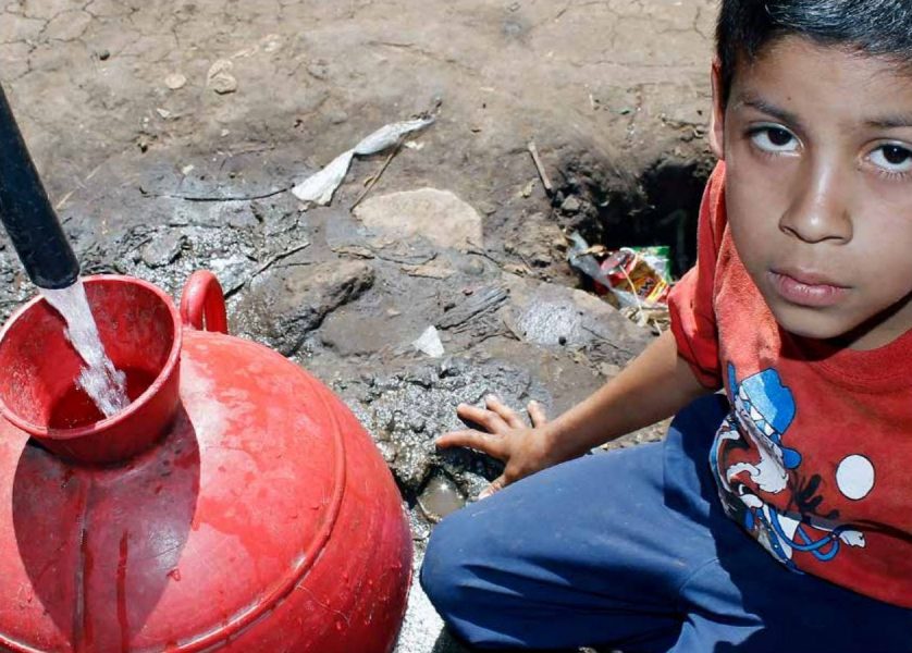 Ett barn fyller en behållare med vatten vid en allmän vattenpump i Los Pinos i staden Ahuachapán i El Salvador.