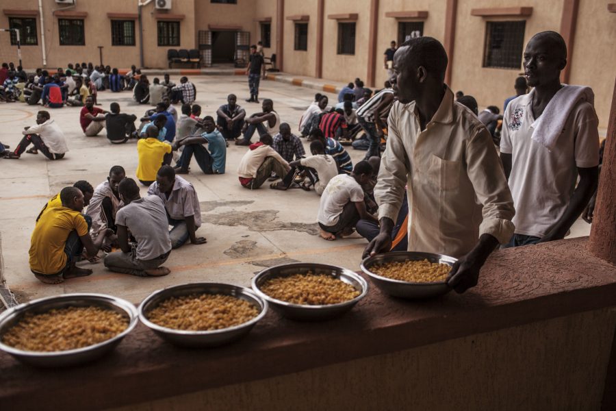En migrant håller en skål med pasta under en lunch i ett flyktingförvar i Libyen.