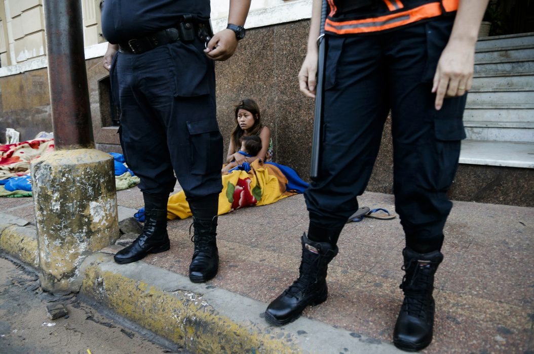 An Ava Guarani woman sits with her baby near the entrance of the Housing and Urban Affairs Ministry as she takes part in a protest demanding the return of ancestral lands, in Asuncion, Paraguay, Thursday, March 21, 2019. (AP Photo/Jorge Saenz) En kvinna sitter med sin bebis nära ingången till bostads- och stadsdepartementet i Asuncion, Paraguay, där hon deltar i ett protest som kräver att de får tillbaka sina förfäders landområden