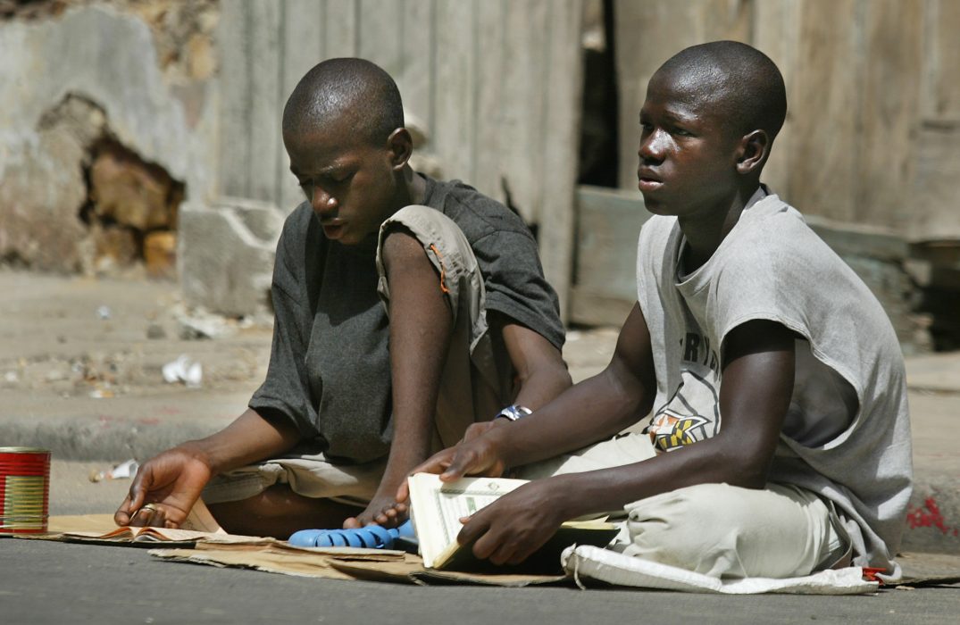 Two talibes read Koranic verses after begging to worshippers leaving a mosque after prayers in Dakar, Senegal, Oct. 3, 2003. (AP Photo/Ben Curtis) Barn tvingas tigga, misshandlas om de inte kan citera koranen och lever under svåra förhållanden