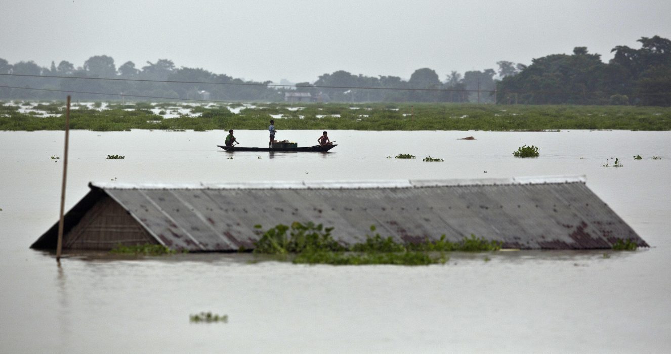 Bybor ror förbi ett hus i östra delstaten Assam i Indien, som drabbats hårt av regnen.