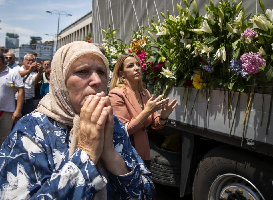 Kvinnor visar sin respekt inför de kistor som bilen som åker genom Sarajevo bär på: 33 män och offer i massakern Srebrenica har identifierats det senaste året.