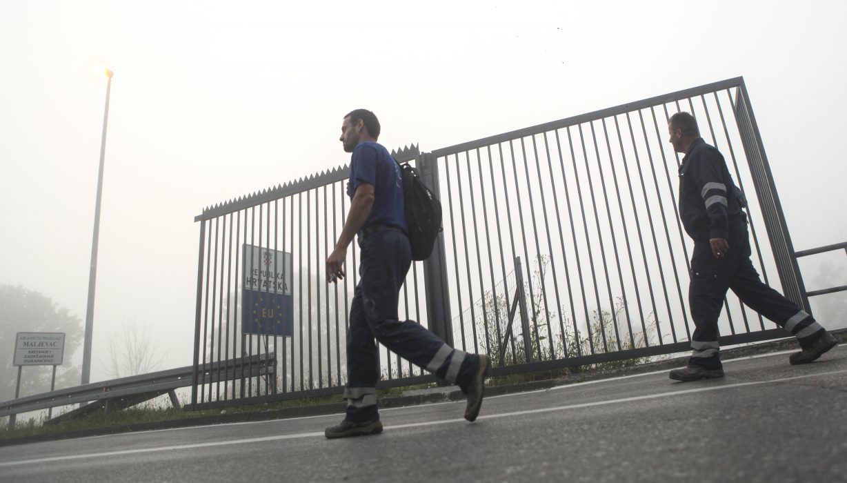 Two men walk past a section of the fence along the border between Croatia and Bosnia near the village of Maljevac, Croatia, Tuesday June 11, 2019. Croatian police are putting up a fence along the border crossing with Bosnia where thousands of migrants have been stuck looking for ways to move West. (AP Photo/Almir Alic) En gränsövergång mellan Bosnien och Kroatien