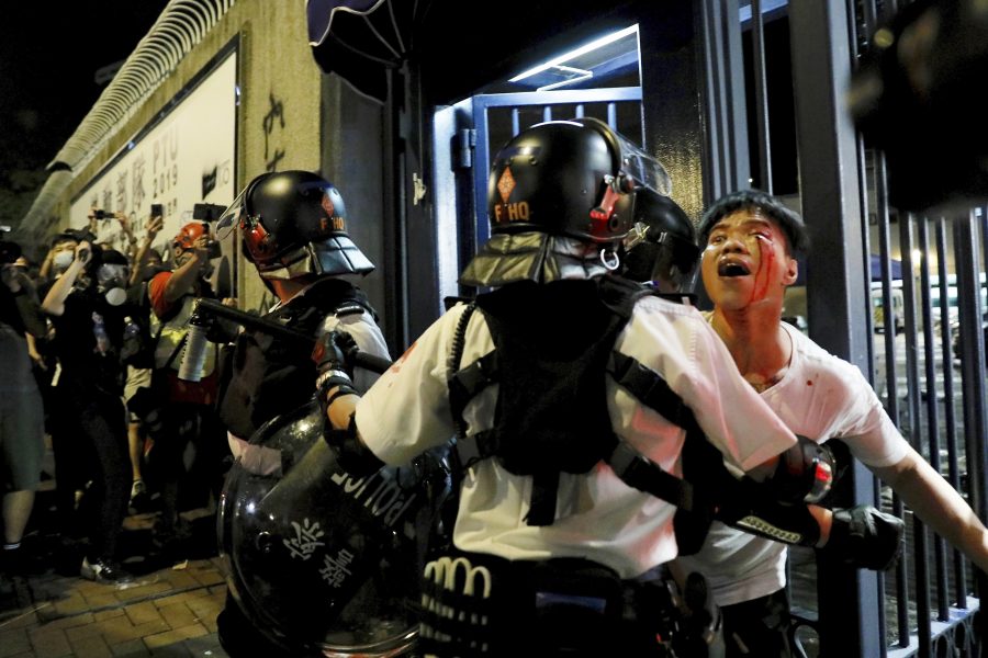 En blödande man förs bort av polis under nya protester i Hongkong under tisdagskvällen.